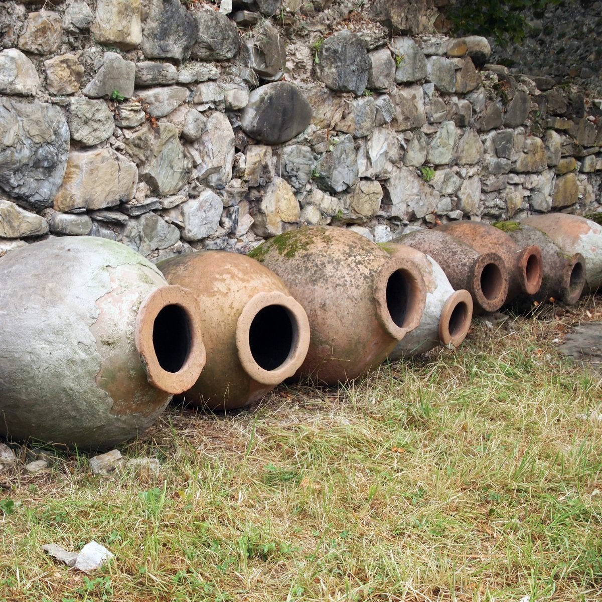 Ancient qvevri vessels by a stone wall